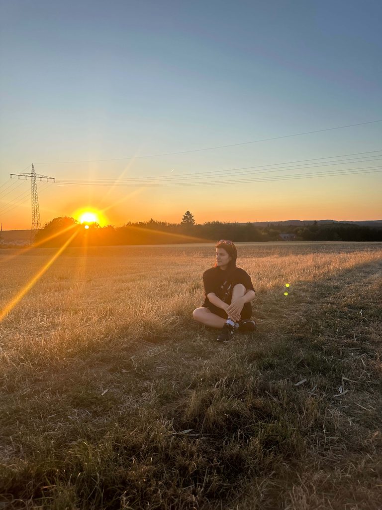Babsi Weber, SEO Expertin sitzt auf einem Feld bei Sonnenuntergang.